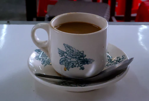 a cup of coffee on a saucer with a spoon