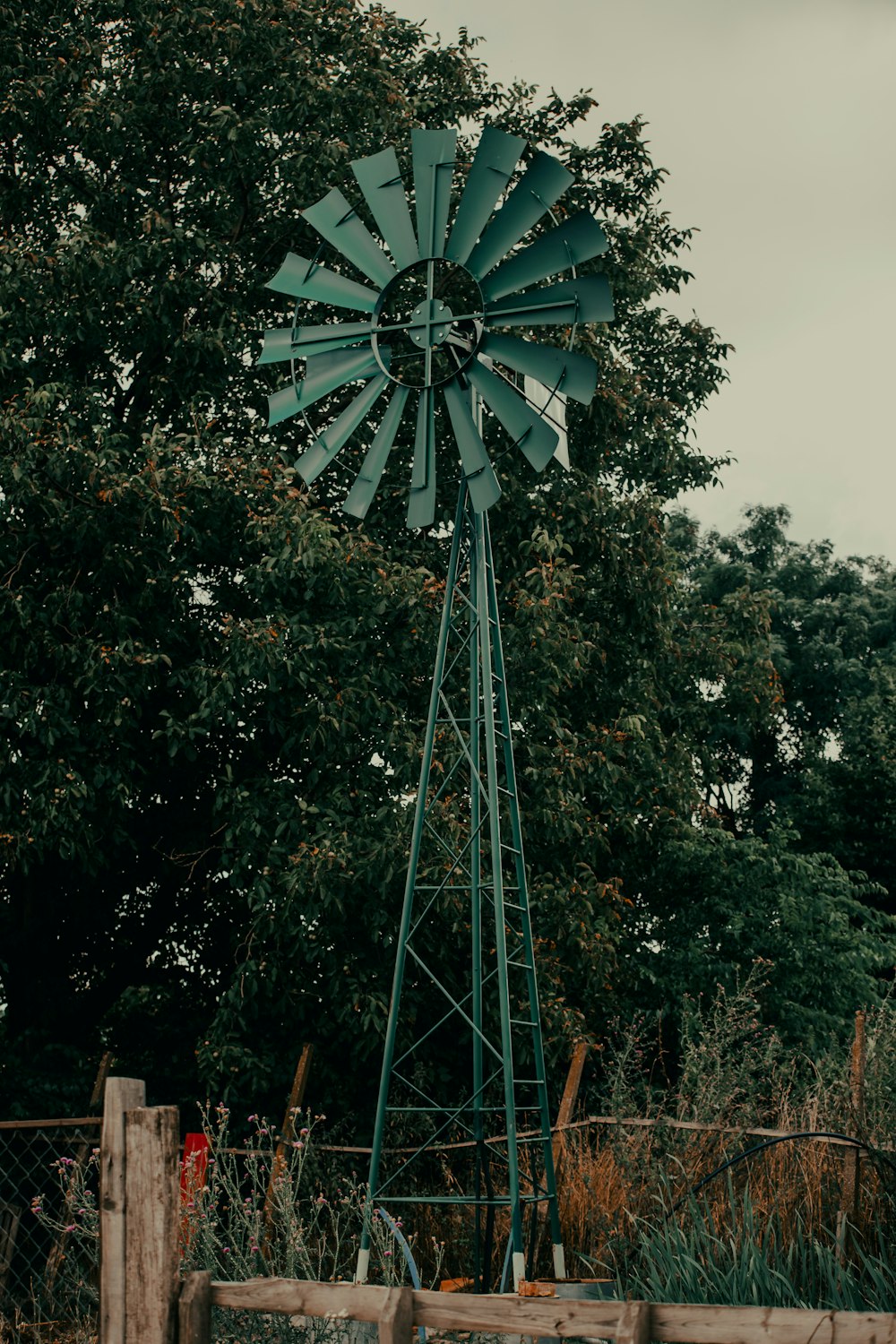 a green windmill sitting next to a wooden fence
