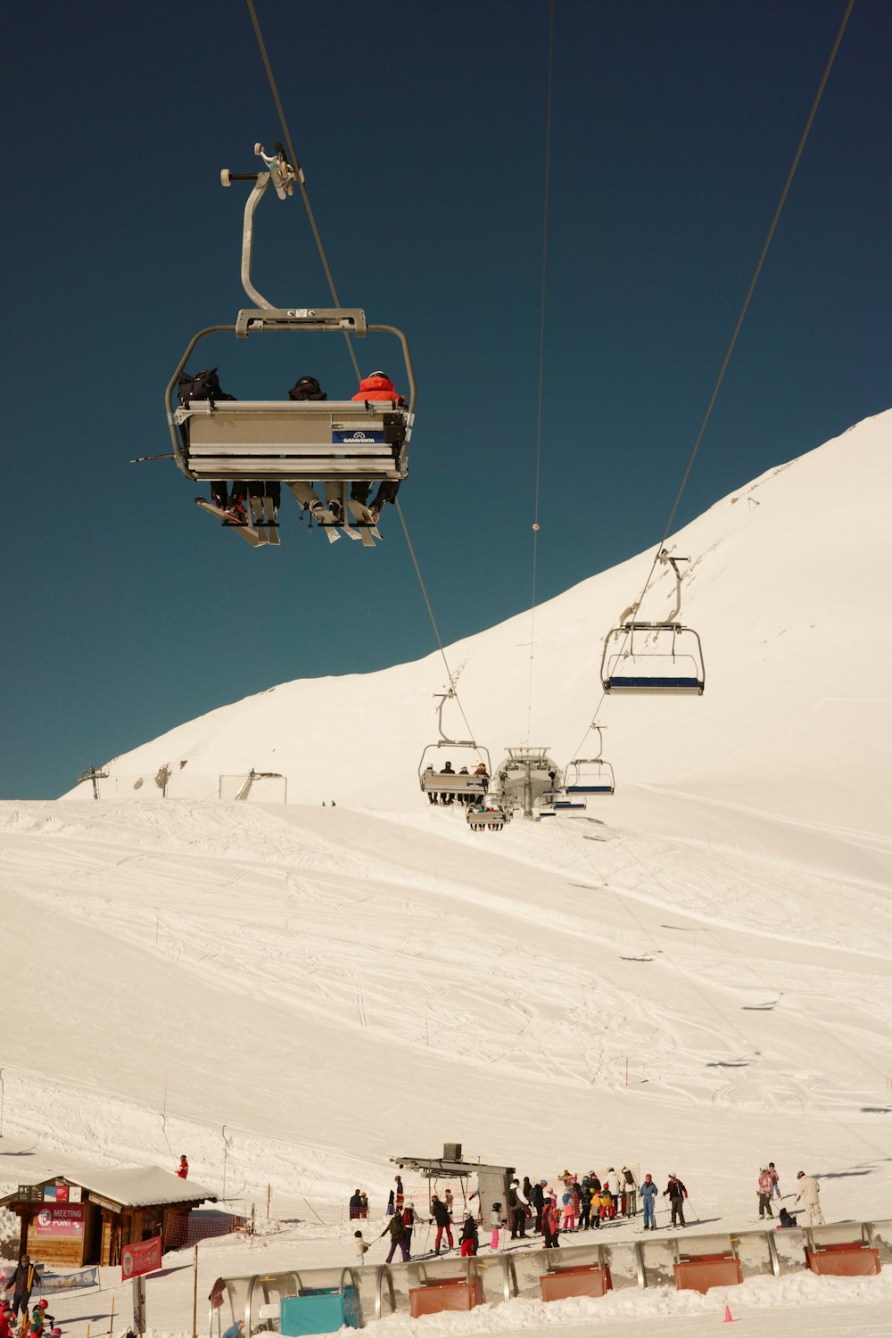 a group of people riding a ski lift up the side of a snow covered mountain