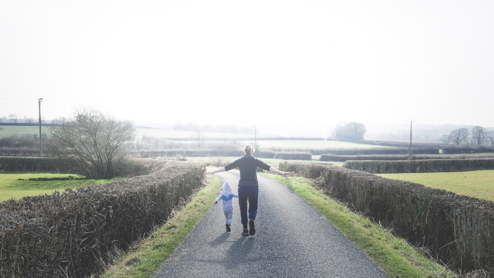 a person walking down a road with a child