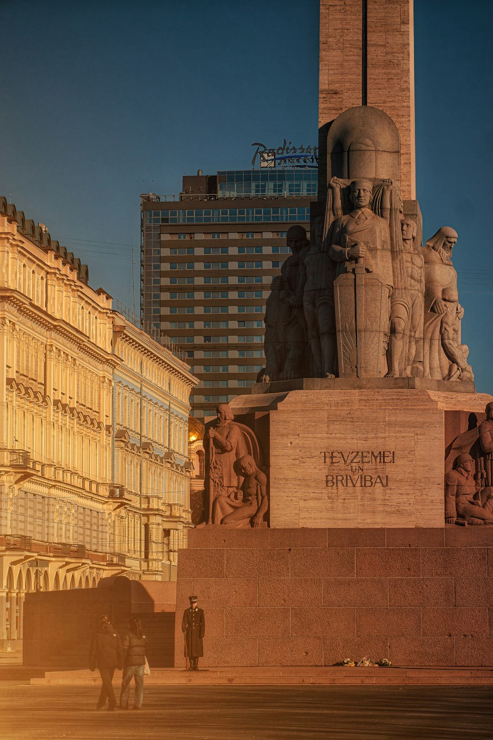 a statue of a man and a woman in front of a tall building