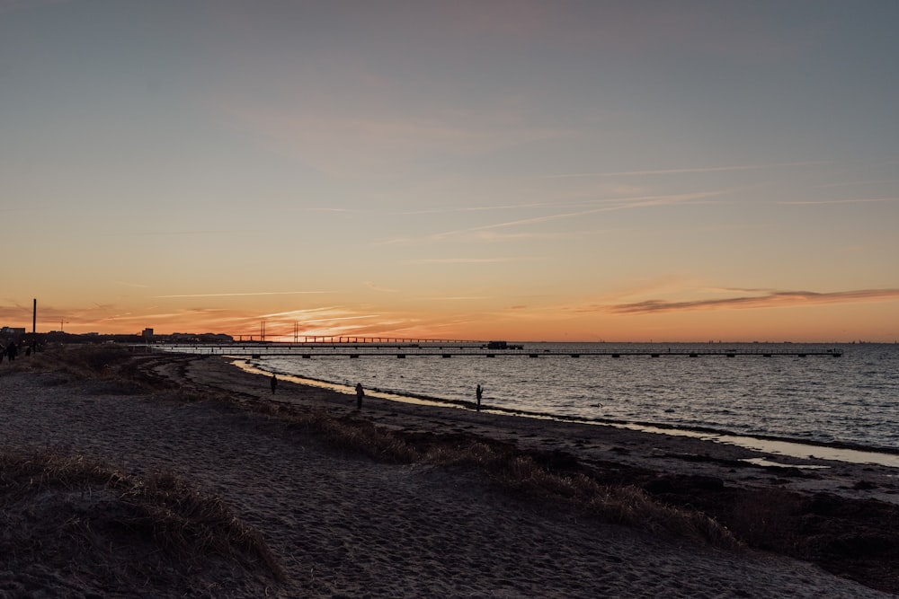 the sun is setting over the water at the beach