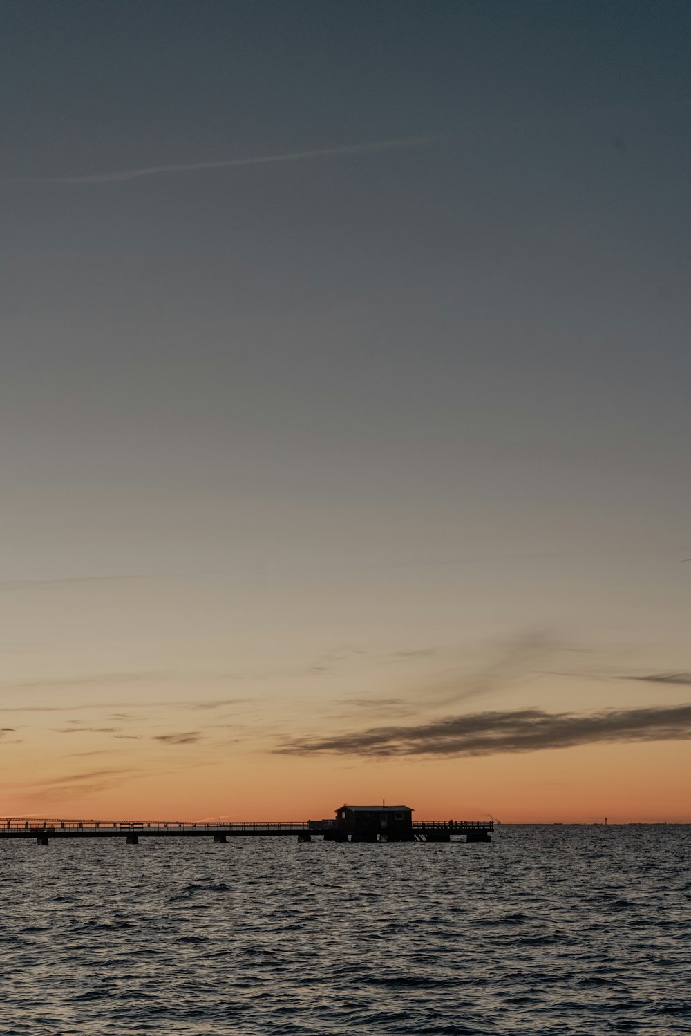 a plane flying over a body of water at sunset