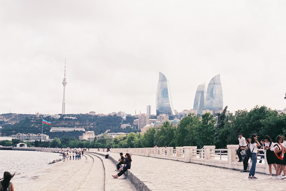 a group of people standing on a stone walkway next to a body of water