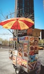 a hot dog cart with an umbrella on top of it
