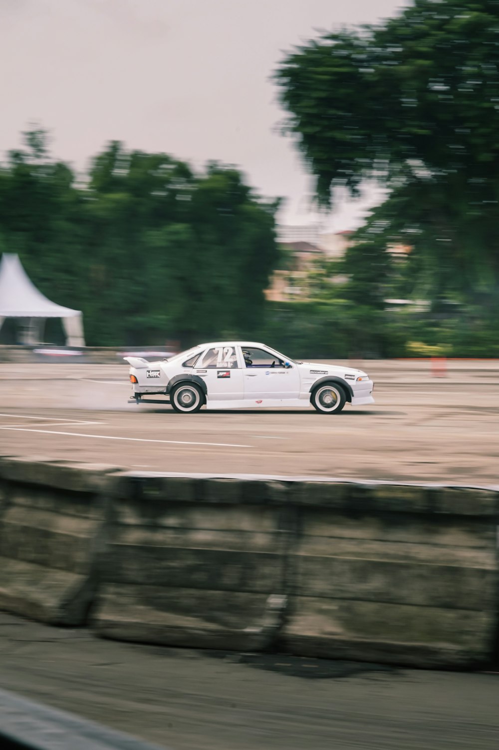 a white car driving down a road next to a forest