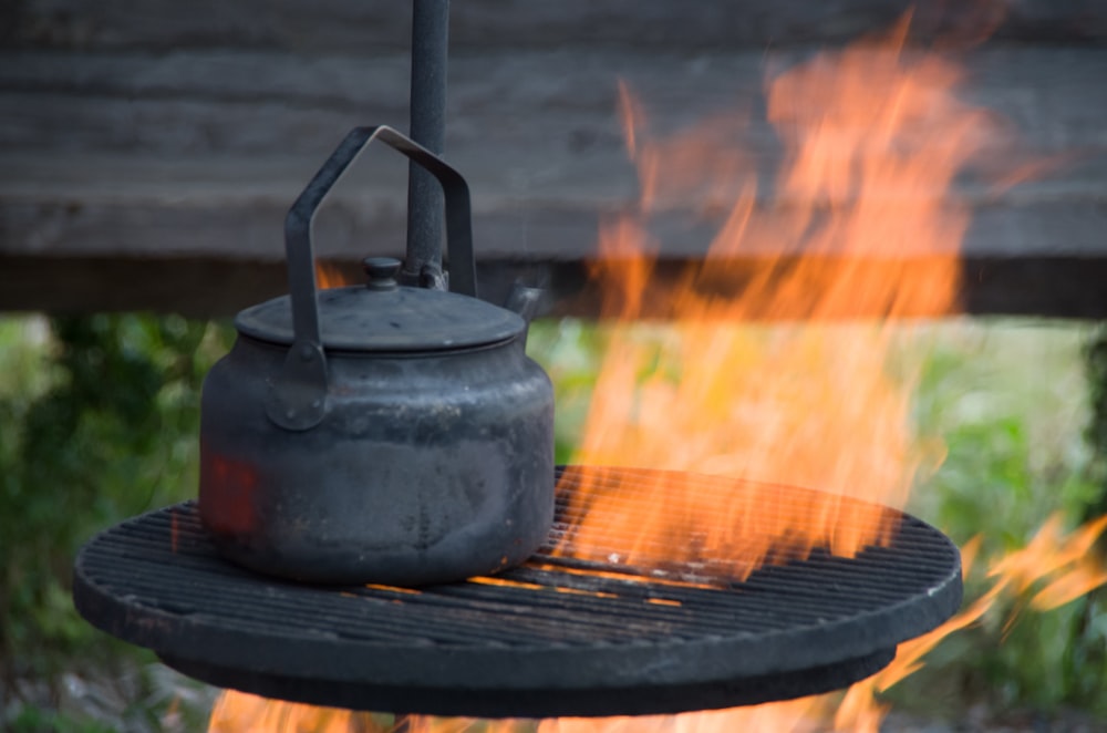 a kettle is on a grill with a flame coming out of it