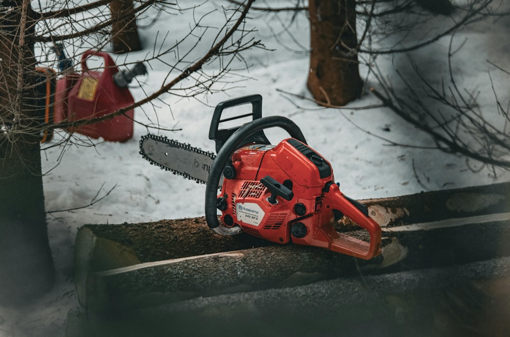 a chainsaw sitting on top of a log in the snow