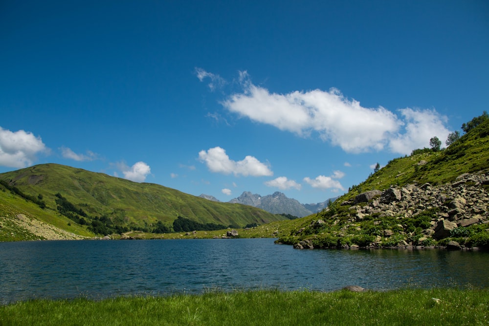 a large body of water surrounded by a lush green hillside