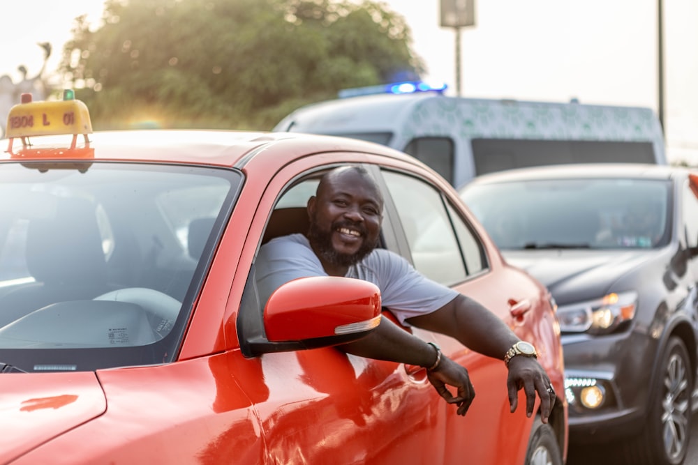 a man leaning out the window of a red car