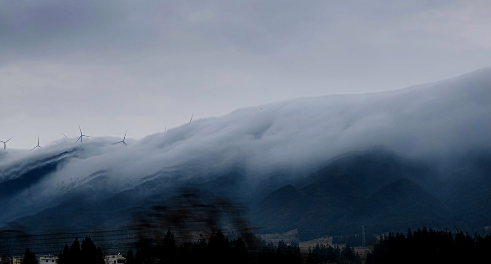 a mountain covered in clouds and wind mills