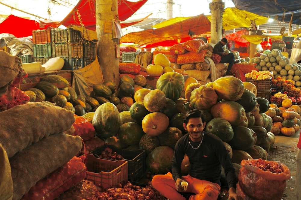 a man sitting on a pile of fruit at a market