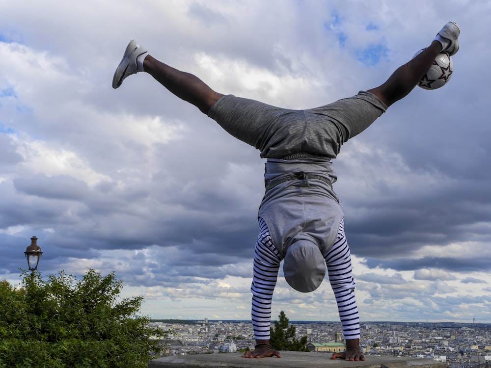 a man doing a handstand on top of a building