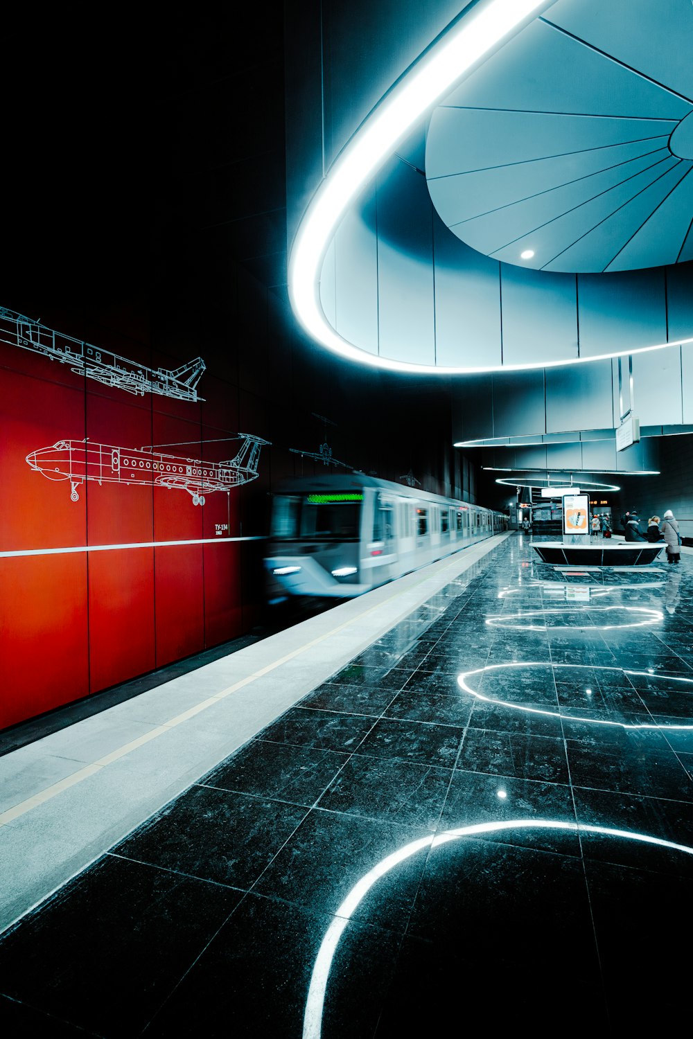 a train traveling through a train station next to a red wall