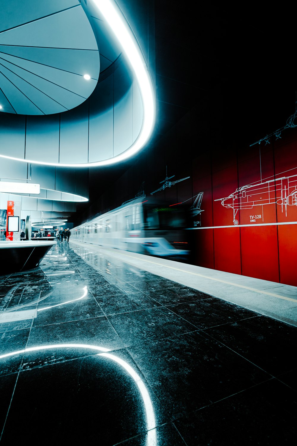 a train traveling through a train station next to a red wall