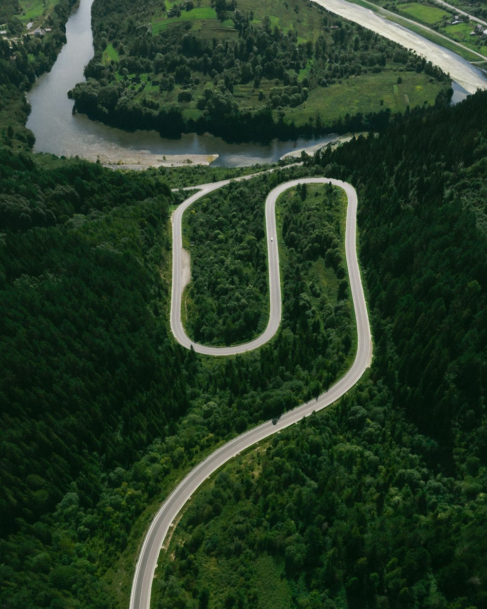 a winding road in the middle of a lush green valley