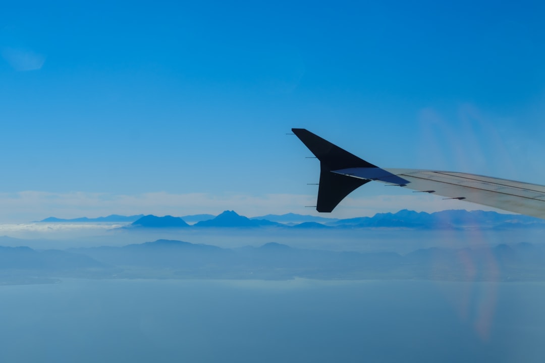 the wing of an airplane flying over a mountain range,