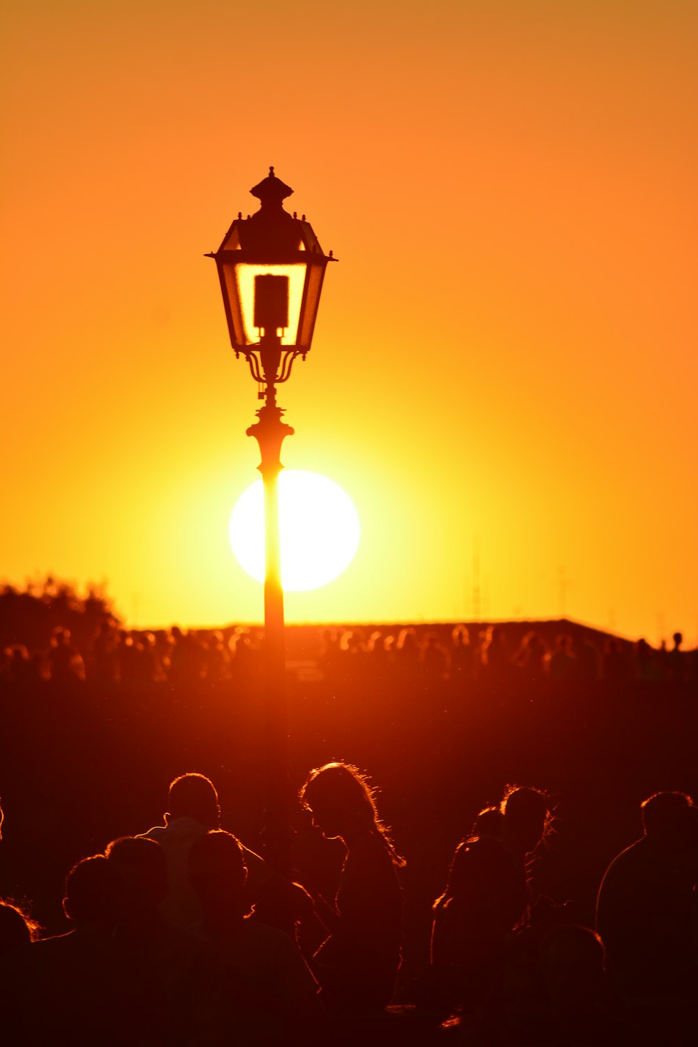 a street light with the sun setting in the background