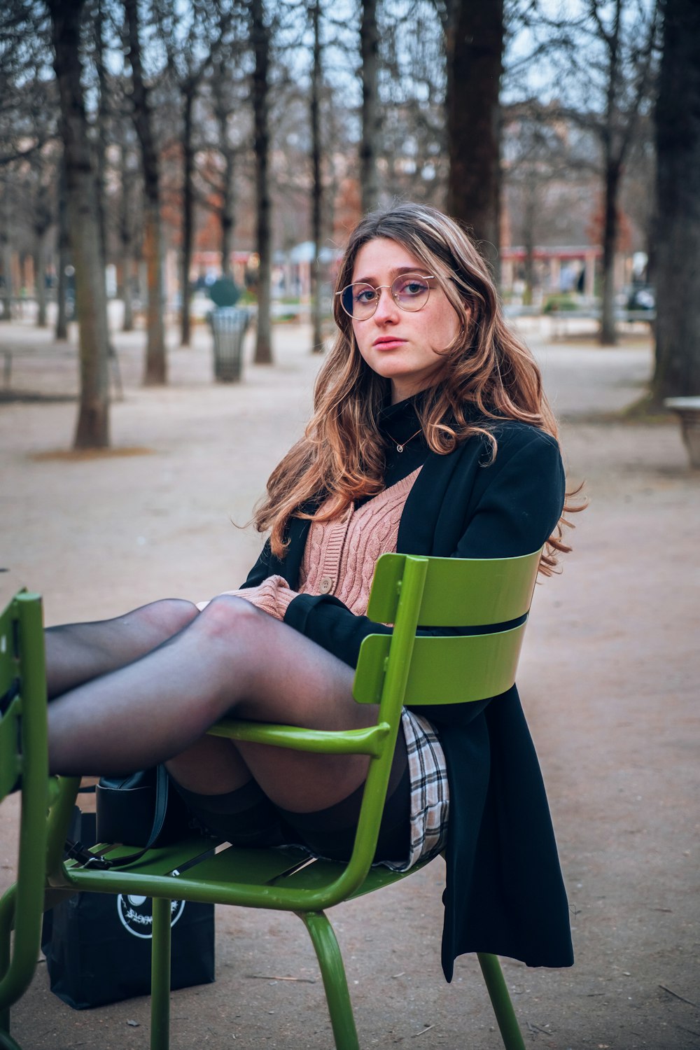 a woman sitting on a green chair in a park