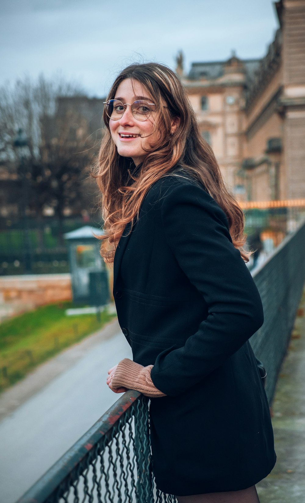 a woman leaning on a fence in front of a building