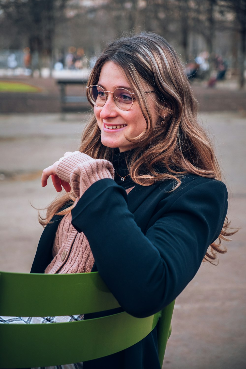 a woman sitting on a green chair in a park