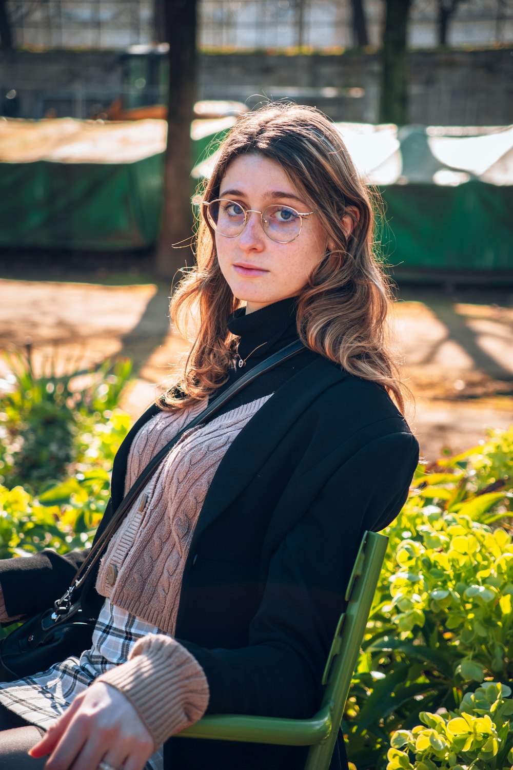 a woman wearing glasses sitting on a green chair