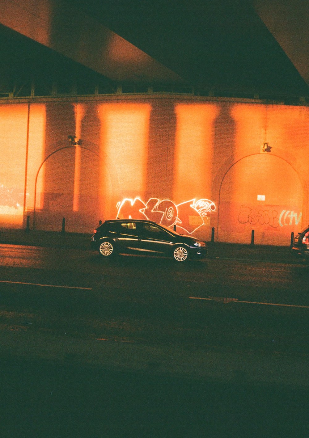 a black car driving down a street next to a tall building