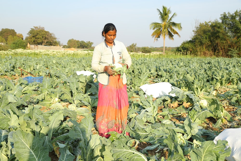 a woman standing in a field of green vegetables