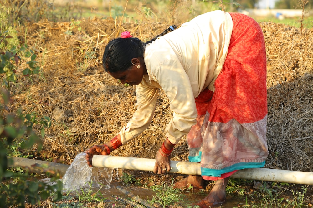 a woman bending over to pick up weeds