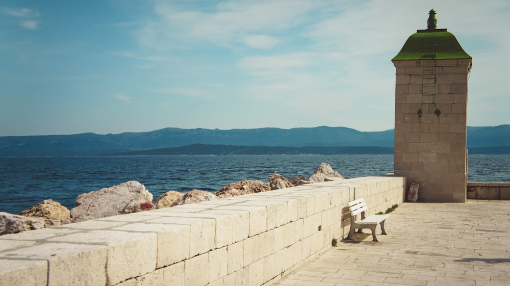 a bench sitting on the side of a stone wall next to a body of water