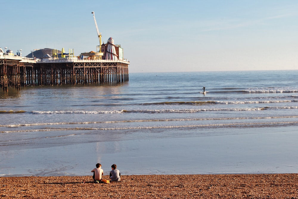 a couple of people sitting on top of a sandy beach