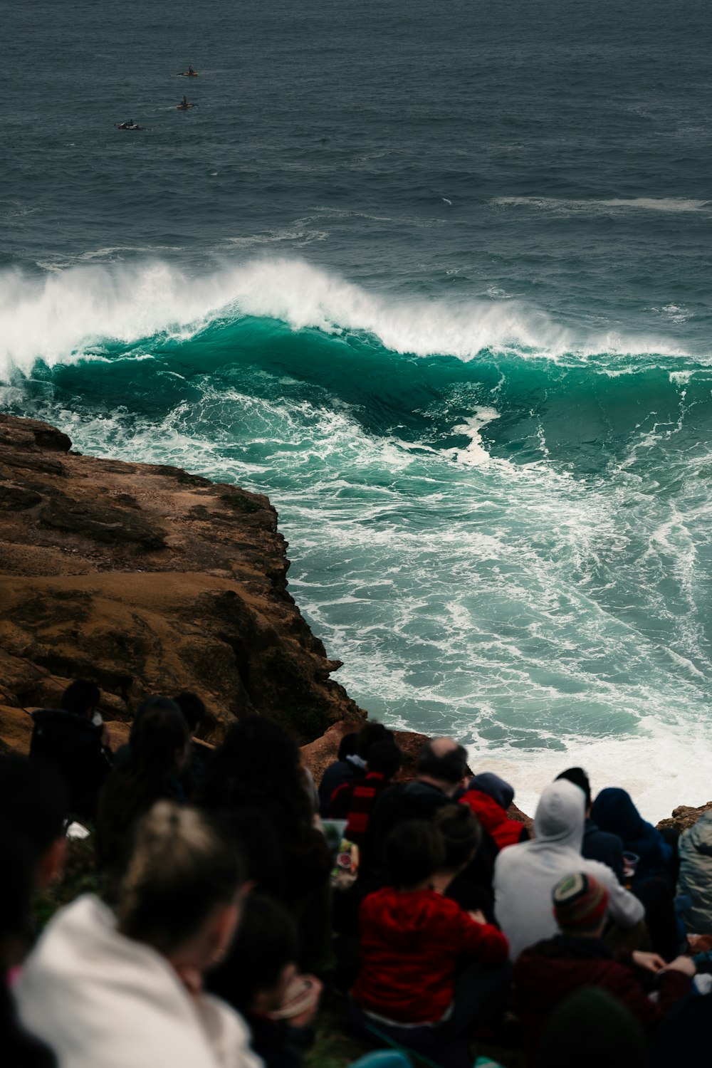 a group of people watching a large wave in the ocean