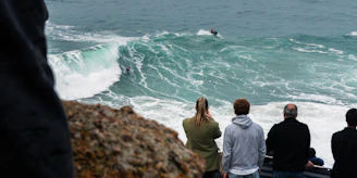 a group of people watching a surfer ride a wave