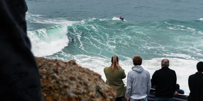 a group of people watching a surfer ride a wave