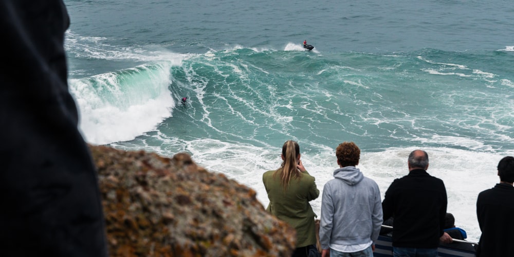 a group of people watching a surfer ride a wave