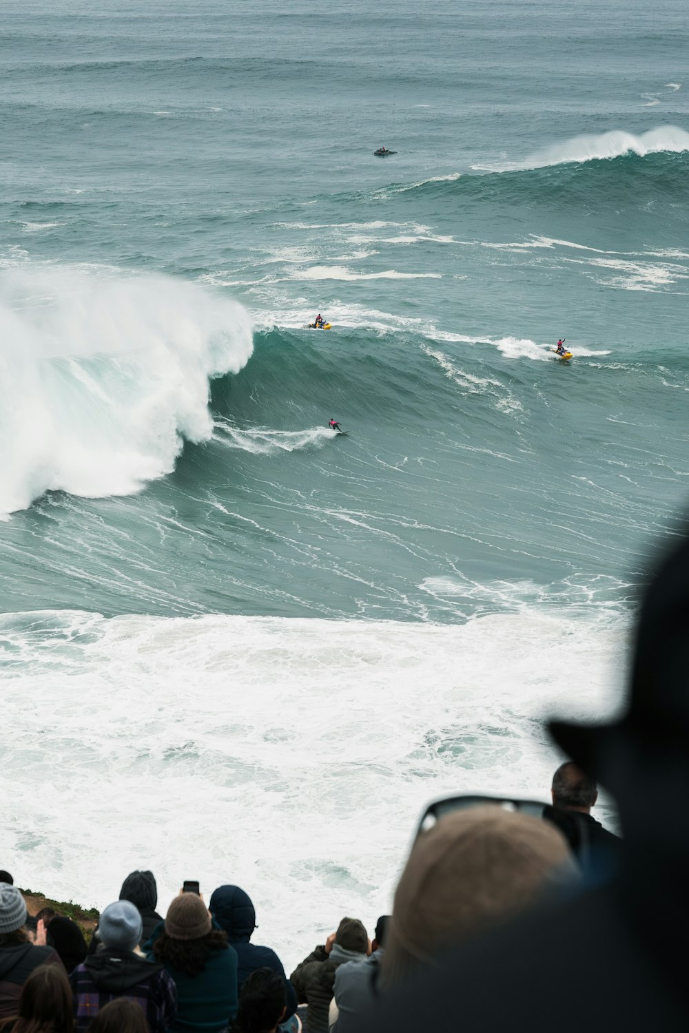 a group of people watching a surfer ride a wave