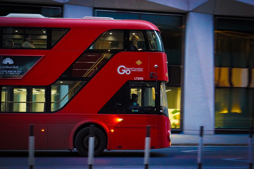 a red double decker bus driving down a street