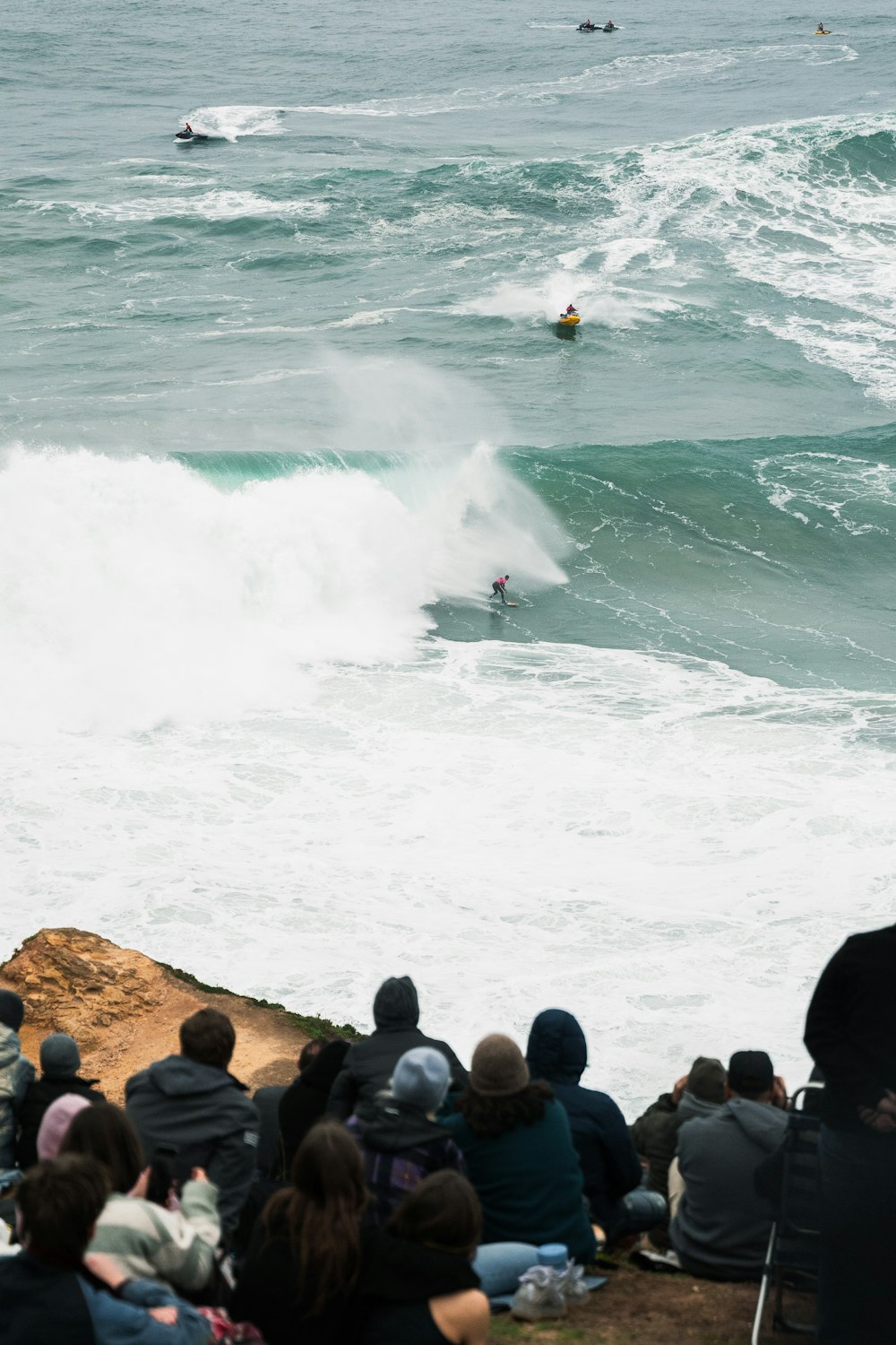 a group of people watching a surfer ride a wave