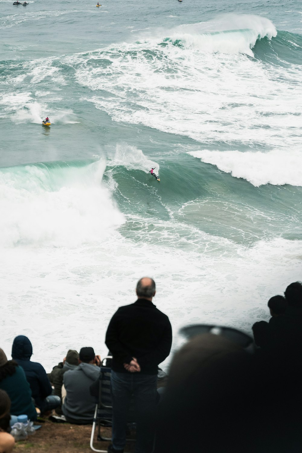 a group of people watching a surfer ride a wave