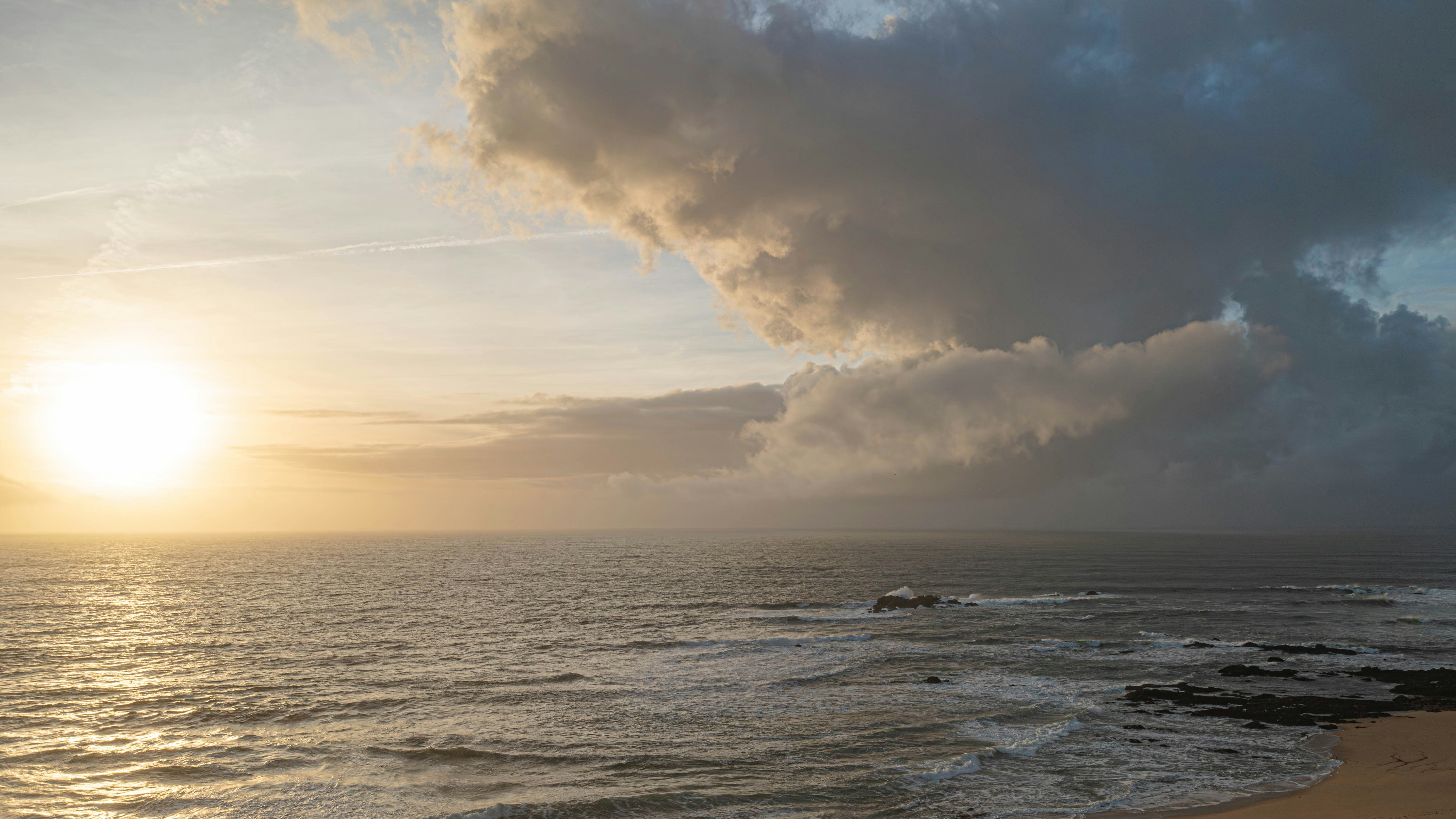 O sol está se pondo sobre o oceano em um dia nublado