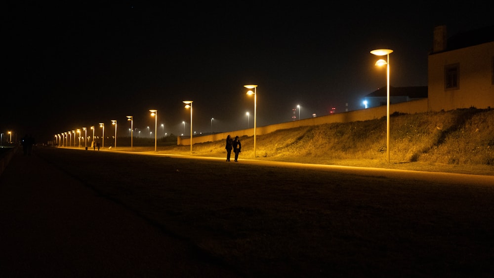 a couple of people walking down a street at night