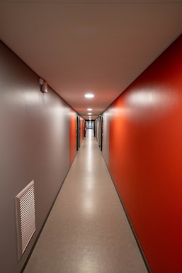 a long hallway with red walls and white floors