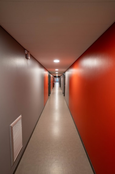 a long hallway with red walls and white floors