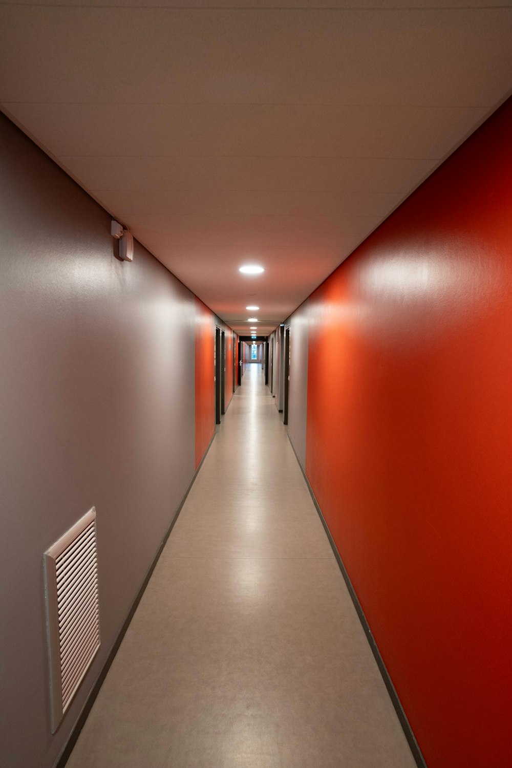 a long hallway with red walls and white floors