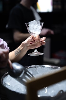 a person holding a wine glass with ice in it