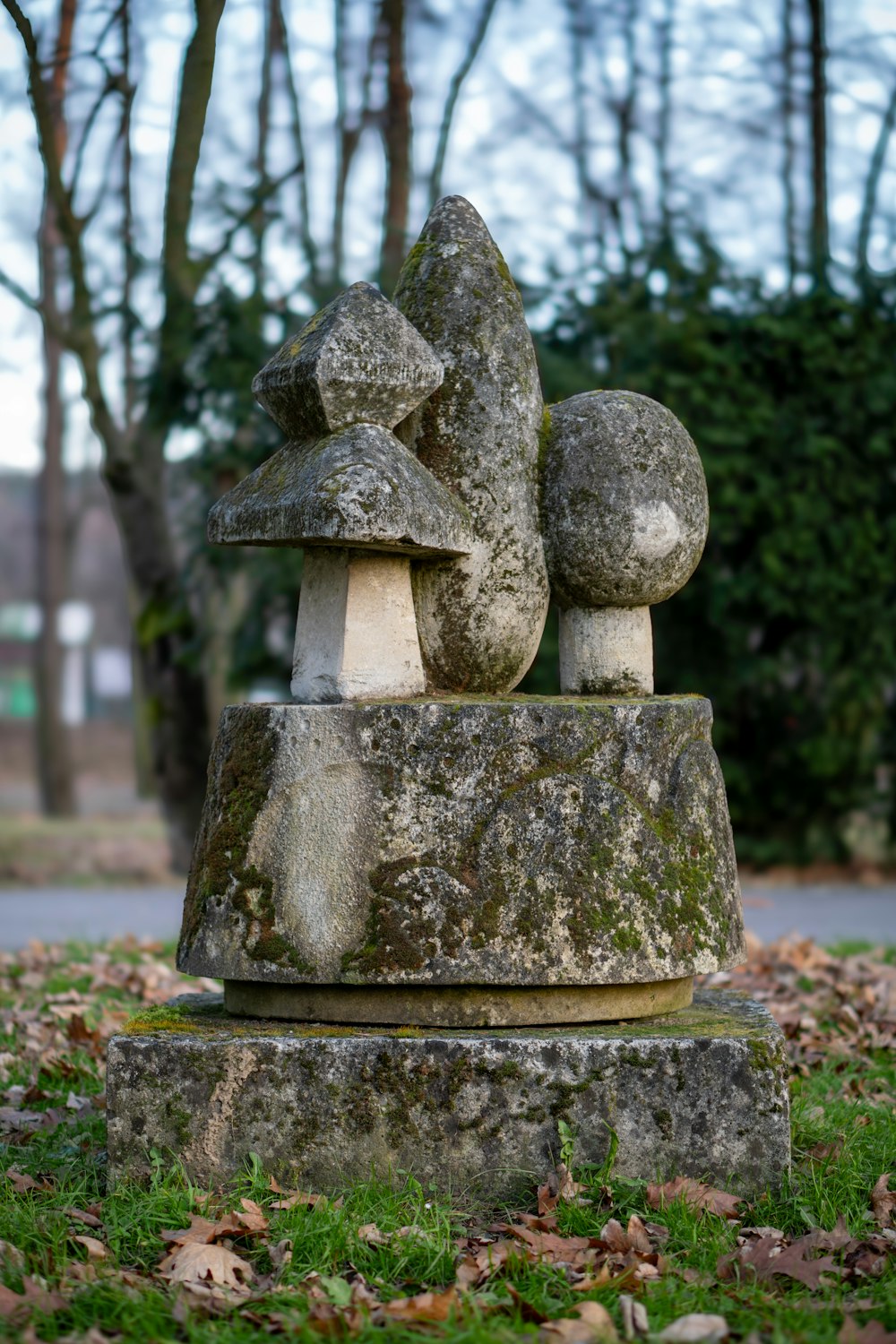 a stone sculpture in a park with trees in the background