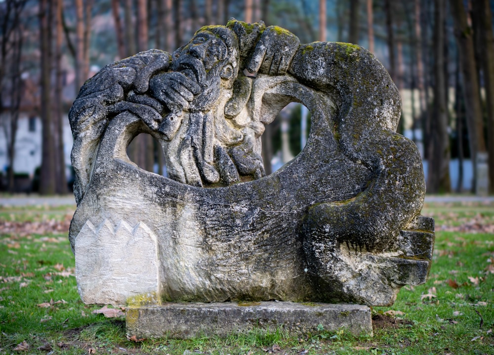 a stone statue of a lion in a park