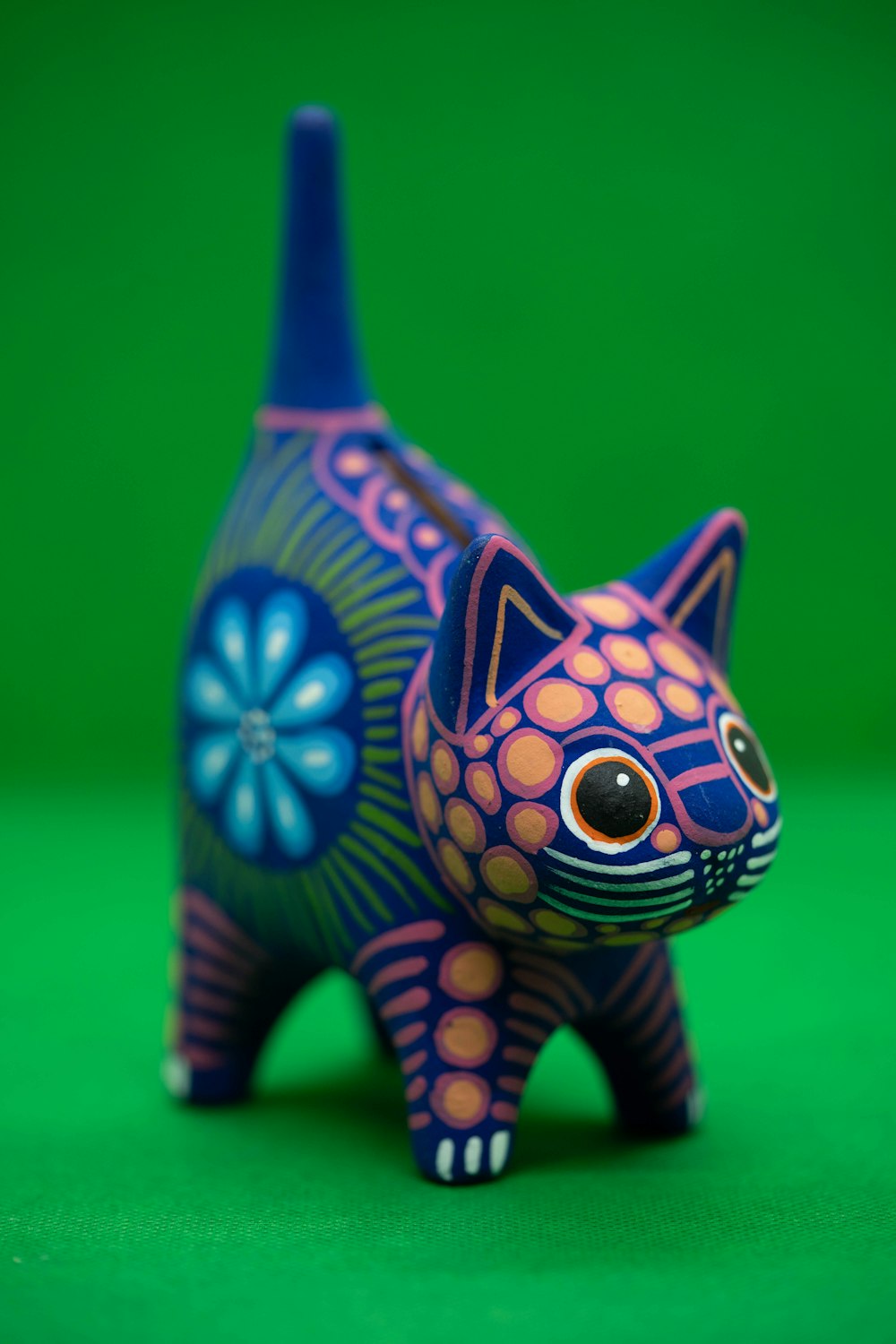 a colorful cat figurine sitting on a green surface
