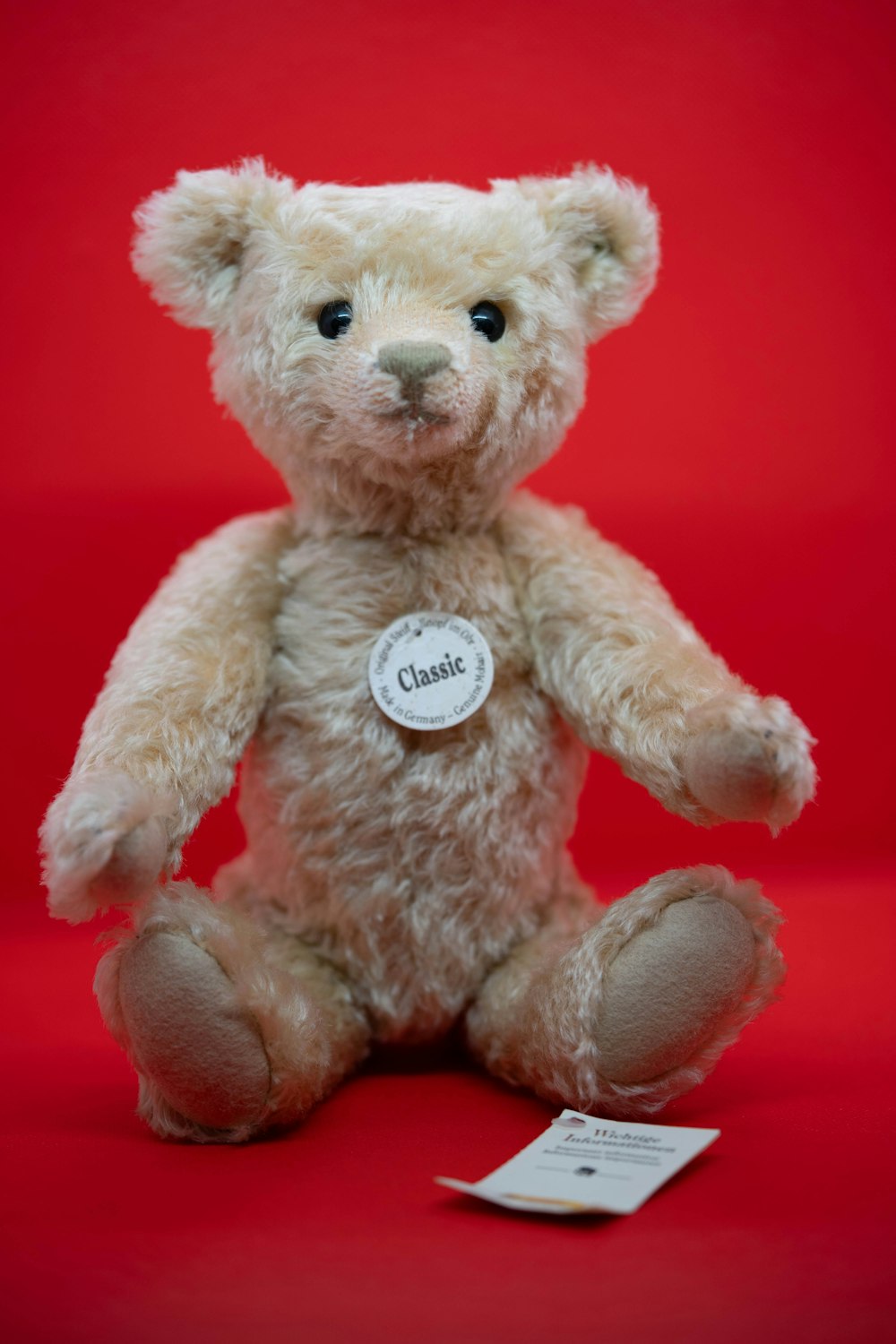 a white teddy bear sitting on a red background