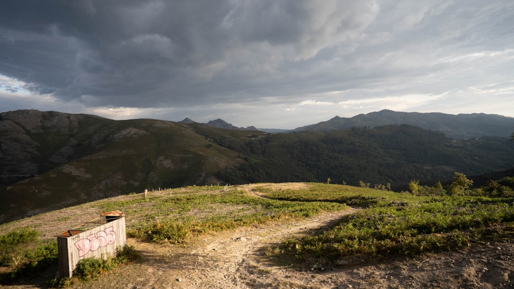 a dirt path leading to a sign on top of a hill